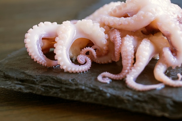 Small marinated octopuses on a black background.