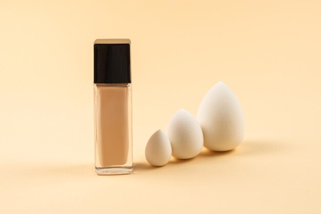 Small medium and large  white beauty blender and makeup foundation on beige background Top view