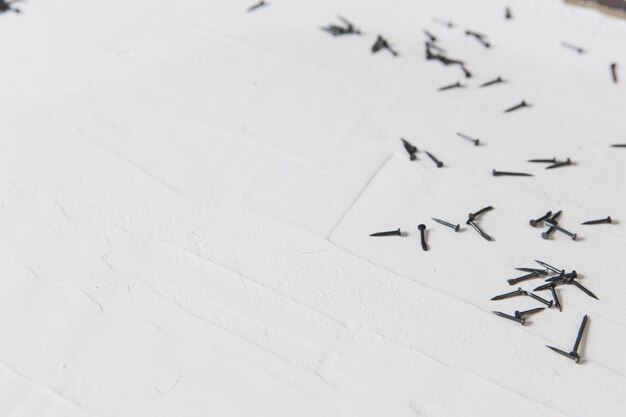 Small metal nails closeup on white plastered surface