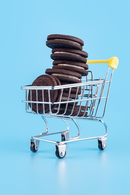Small metal supermarket shopping trolley full of fresh sweet pastries in form of chocolate cookies