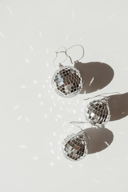Piccole palle da discoteca a specchio con ombre di luce solare su sfondo bianco concetto di festa di celebrazione delle vacanze estetiche minime