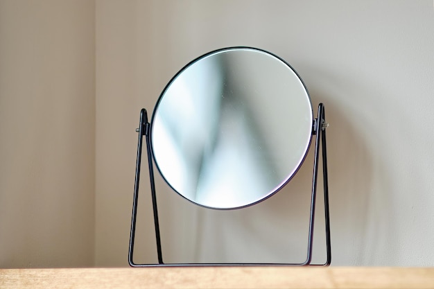 Foto un piccolo specchio si erge su una mensola di legno contro la parete chiara della stanza