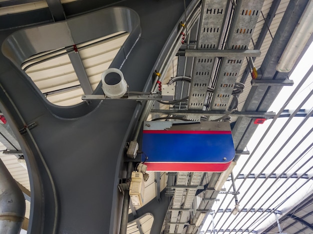 The small modern megaphone is hanging on the metal beam of the platform roof for announcements inside the urban train station above view with the copy space