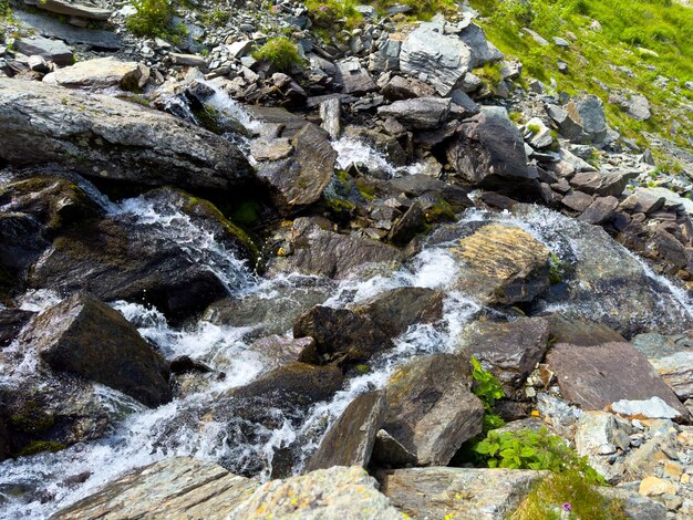 A small mountain stream flows through the stones on the slope