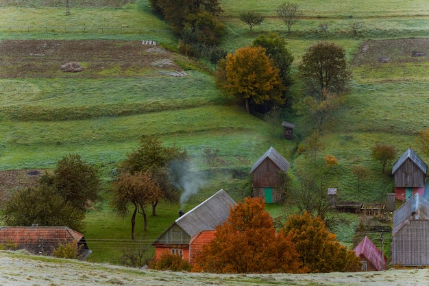 Piccolo villaggio di montagna sulla collina con alberi colorati verdi, arancioni e gialli