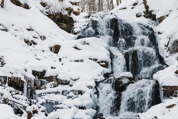 Small mountain waterfall of icy water flow