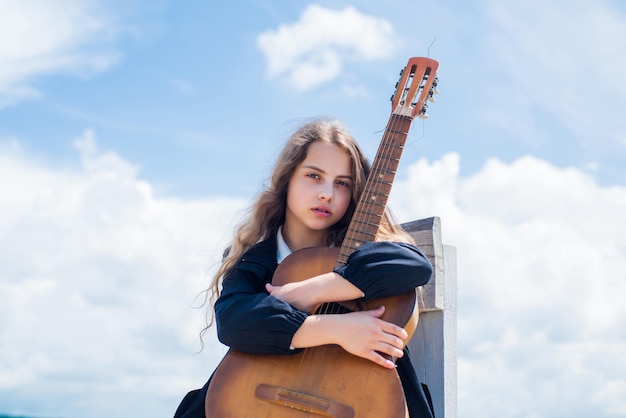 Piccoli amanti della musica contenuti musicali gratuiti musicista adolescente che suona la chitarra ritratto di bambino che suona la chitarra sullo sfondo del cielo playlist romantica estiva chitarrista che intrattiene gli ospiti alla festa