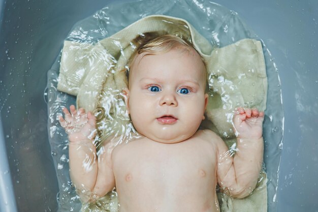 Foto un piccolo neonato di 5 mesi sta facendo il bagno in una vasca da bagno.