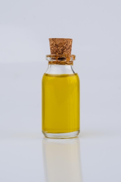 маленькая бутылка масла, изолированные на белом фоне. желтая жидкость в небольшой стеклянной бутылке.