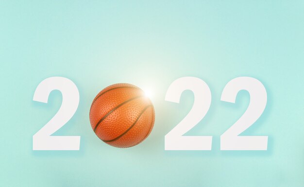 Small orange ball for basketball sport game on blue background\
with text 2022.