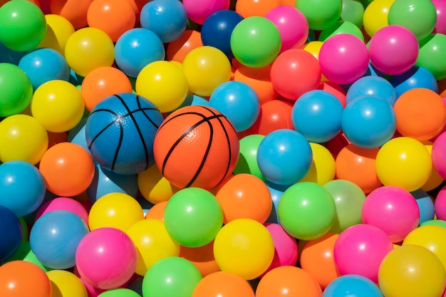 볼 풀에 다채로운 플라스틱 공이 있는 작은 주황색 및 파란색 농구 장난감