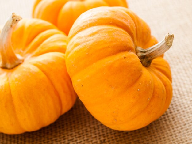 Small orange pumpkins on burlap fabric.