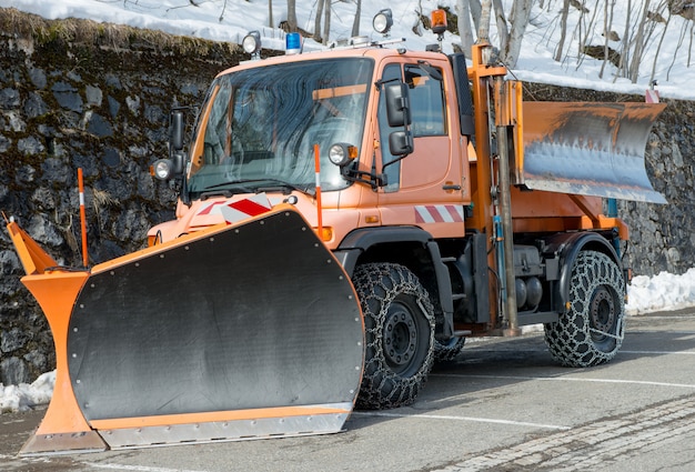 Small orange truck using snow plow