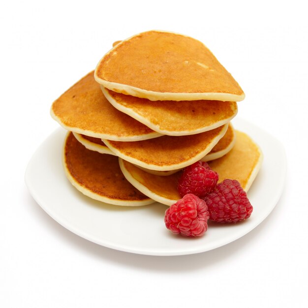 Small pancakes topped with berries on white