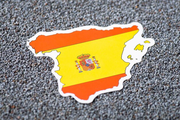 Small paper flag and map of Spain in poppy seed