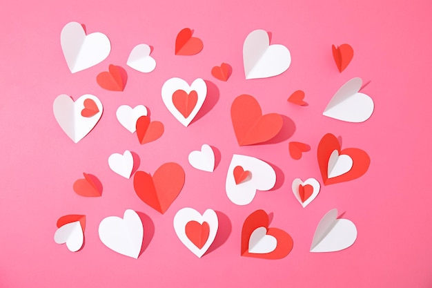 Small paper hearts on color background top view