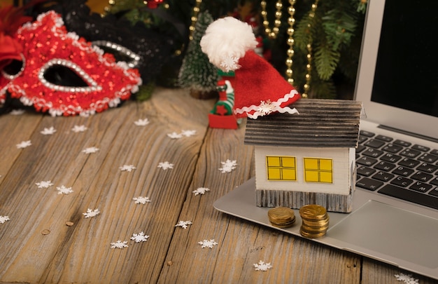 Small paper house with Santa Claus hat on it placed on laptop Closeup