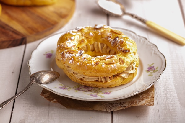 Piccola pasticceria paris brest in un vecchio piatto su un tavolo di legno bianco