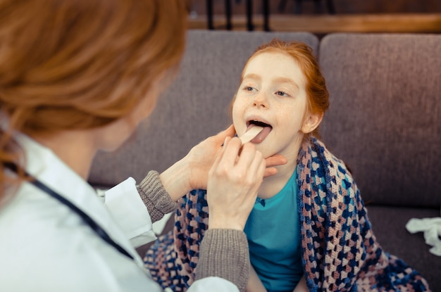 Photo small patient. nice cute girl opening he mouth while looking at her doctor