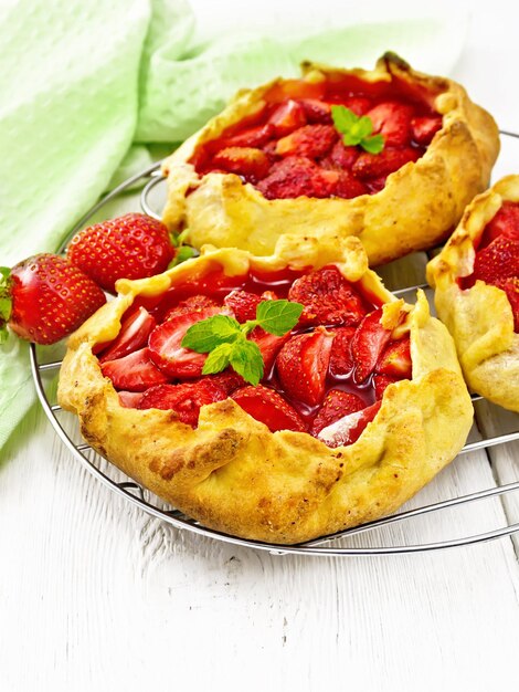 Small pie with strawberries on a metal grille napkin on background of wooden board