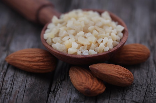 Small pieces of chopped almonds in wooden scoop with whole ones