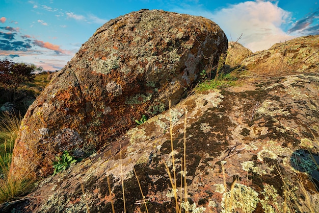 A small pile of old stones in a large green-yellow field against the backdrop of a fantastically beautiful blue sky