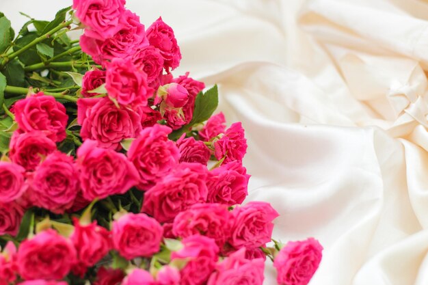 Small pink bush roses on a white silk background with a place for text