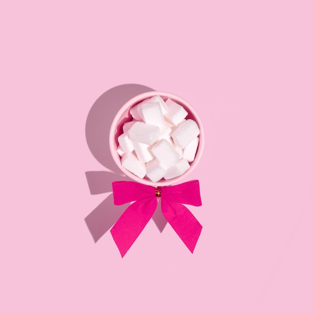 Small pink cups filled with sugar cubes on a soft pink background. Flat lay composition.