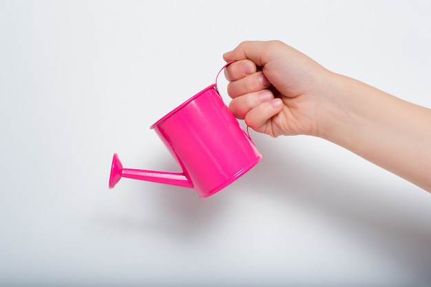 Small pink watering can in a children's hand