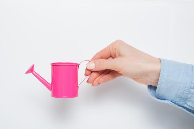 Small pink watering can in a female hand