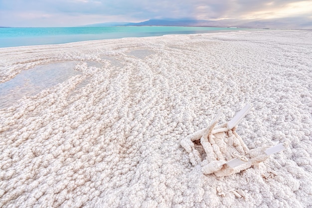 Small plastic chair completely covered with crystalline salt on shore of dead sea, closeup detail