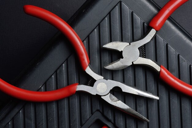 Small pliers and pliers lie on a closed toolbox. view from above.