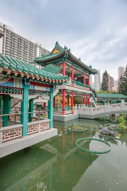 Small pond in God Wish Garden among Skyscrapers of the City in Wong Tai Sin Temple in Kowloon, Hong Kong