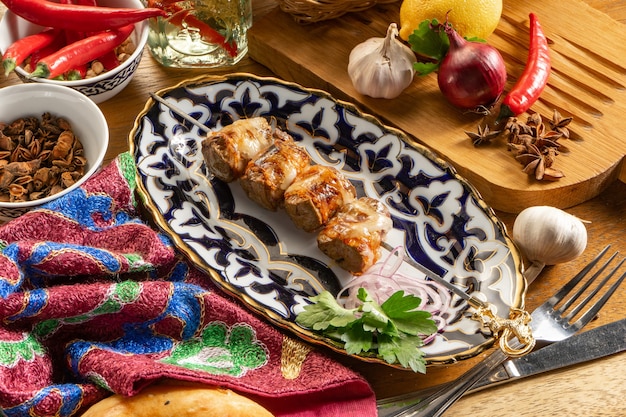 A small portion of shish kebab made from homemade sausages with red onion and parsley on a plate with a traditional Uzbek pattern