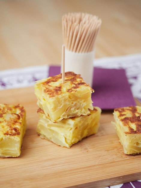 Small portions of potato omelet served as typical Spanish tapas with chopsticks called pinchos close up view