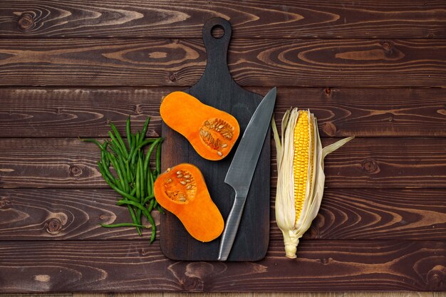 Small pumpkin cut into halves on wooden cutting board with knife