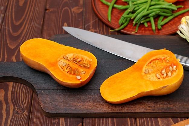 Small pumpkin cut into halves on wooden cutting board