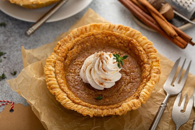 Photo small pumpkin pie with whipped cream and cinnamon