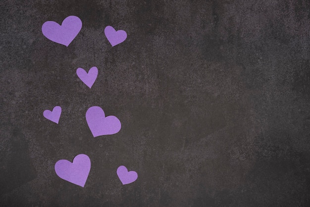 Small purple hearts on a dark background copy space