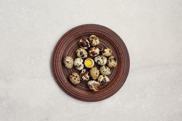 Small quail eggs in a clay plate on light stone table