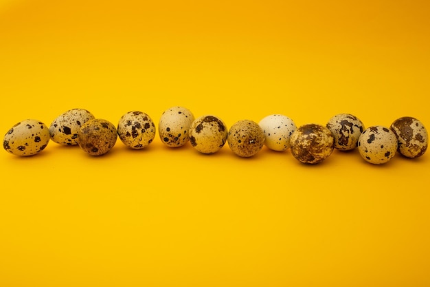 Маленькие перепелиные яйца лежат на желтом фоне, минимализм для рекламы