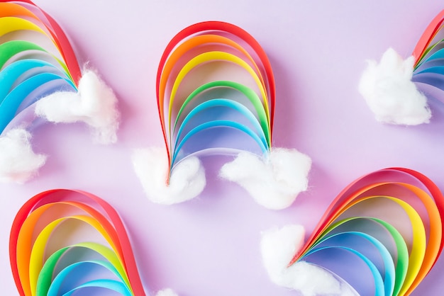 Photo a small rainbow of colored paper with clouds of snow, creativity with their hands on a light background. diy