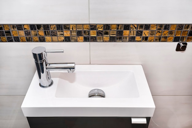 Foto un piccolo lavandino rettangolare con un rubinetto d'argento a sinistra in un bagno a piastrelle