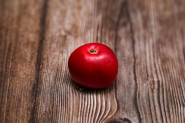 Small red apple on a brown wooden table close-up. High quality photo