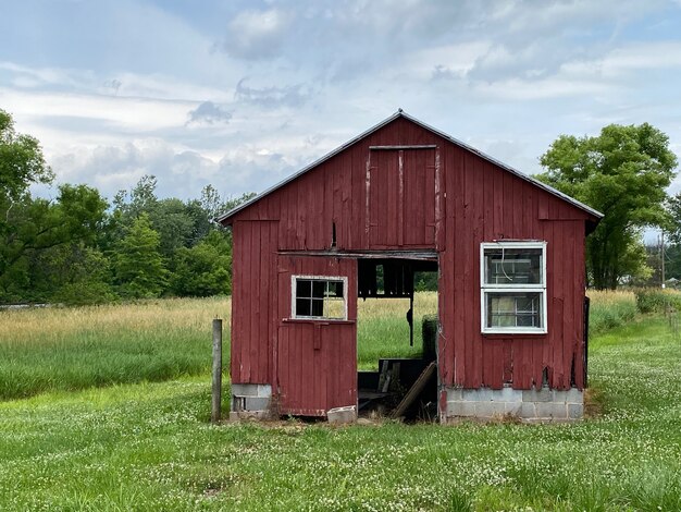 Small red barn in a field with trees in the background