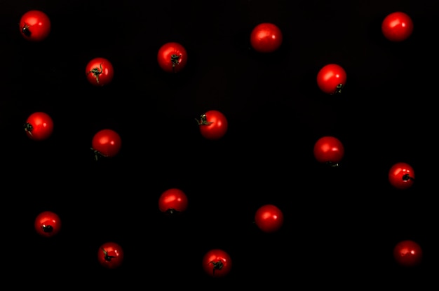 Small red cherry tomatoes on black background top view