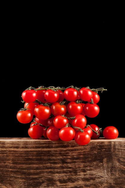 Small red cherry tomatoes on an old brown wooden board, close-up.