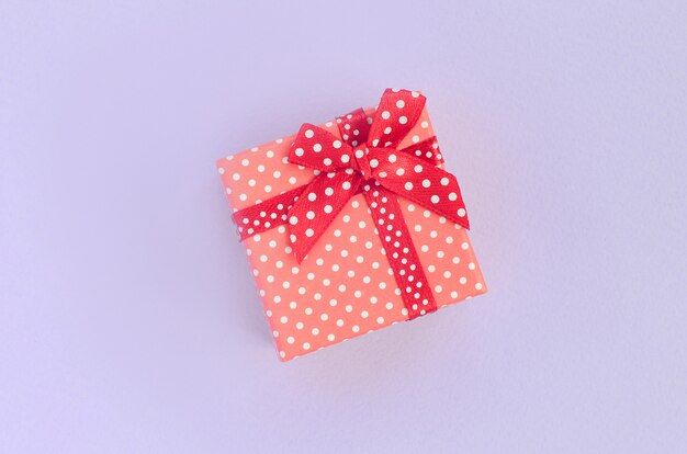 Small red gift box with ribbon lies on violet