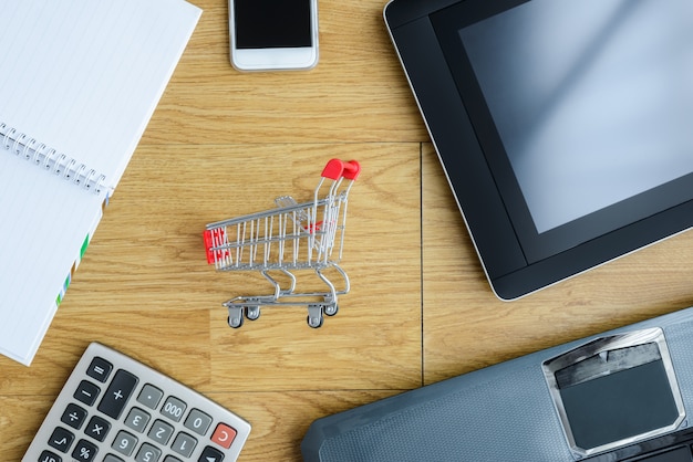 Small red shopping cart, trolley and gadgets on the table