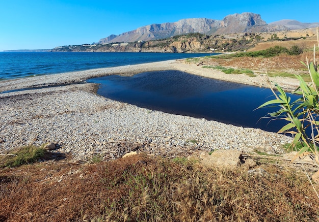 Small river flows into the sea on pebble beach